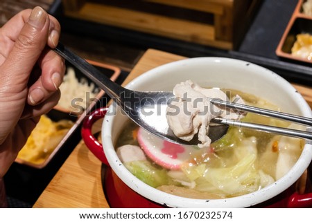 closeup image of woman eating hot pot with vegetables and pork