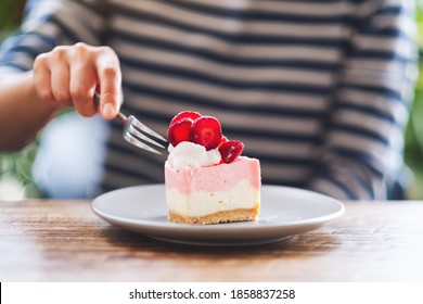 Closeup image of a woman eating a strawberry cheese cake in a plate - Powered by Shutterstock