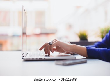 Close-up image of woman hands typing and writing massages on laptop,working on cafe.Overhead of essentials for modern young person.sensual woman reading and working,Urban