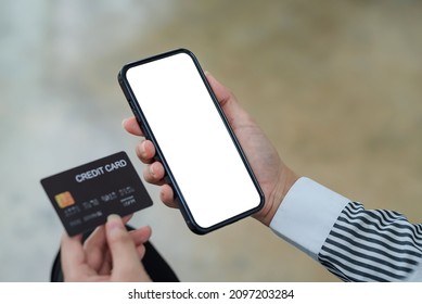 Close-up Image Of Woman Hands Using Smartphone Blank White Screen And Holding Credit Card. Online Shopping Concept. Mock Up.