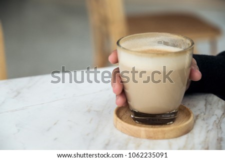 Closeup image of a woman holding coffee glass in cafe