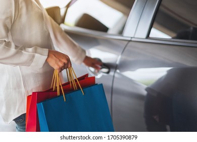 Closeup Image Of A Woman Holding Shopping Bags While Opening Car Door In The Mall Parking Lot