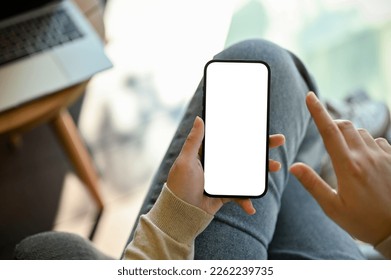 Close-up image of a woman in jeans relaxes sitting in the cafe and using her smartphone. smartphone white screen mockup for display your graphic banner. - Shutterstock ID 2262239735