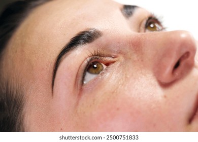 A close-up image of a woman lying down with freshly tinted eyebrows. The focus is on her face and eyes, showcasing the results of the eyebrow tinting procedure. - Powered by Shutterstock