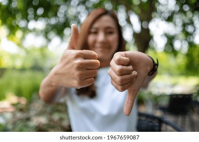 Closeup Image Of A Woman Making Thumbs Up And Thumbs Down Hands Sign