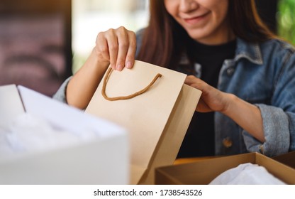 Closeup Image Of A Woman Opening And Looking Inside Shopping Bag At Home For Delivery And Online Shopping Concept