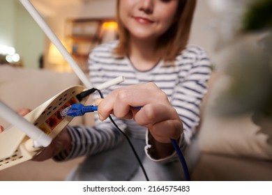 Closeup Image Of Woman Plugging Ethernet Cord In Back Of Modem To Get Faster Speed