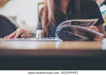 Closeup image of a woman reading a book in modern cafe 