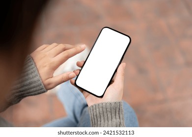 A close-up image of a woman using her smartphone while sitting outdoors. a white-screen smartphone mockup. people and technology concepts - Powered by Shutterstock