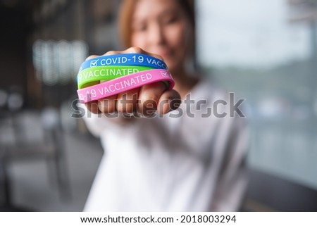 Closeup image of a woman wearing and showing colorful Covid-19 vaccination wristband for health care concept
