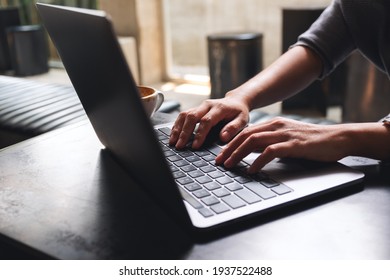Closeup image of a woman working and typing on laptop computer keyboard on wooden table - Shutterstock ID 1937522488