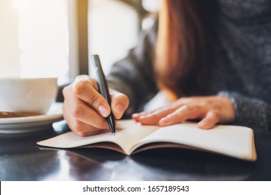 Closeup image of a woman writing on a blank notebook on the table 