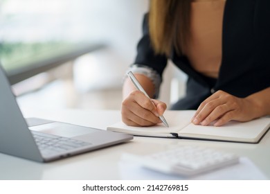 Closeup image of a woman writing and taking note on notebook with laptop in office. - Shutterstock ID 2142769815