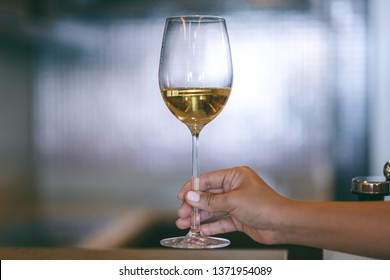 Closeup Image Of A Woman's Hand Holding A Wine Glass With Blurred Background