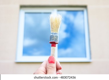 Closeup image of a womans hand with paintbrush while painting window trim, Painter working, painting the house and windows, external works with paint and brush, painting a window frame - Shutterstock ID 483072436