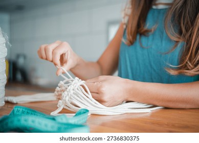 Close-up image of a woman's hands doing macramé. Concept of wom