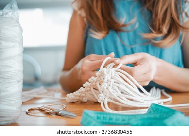 Close-up image of a woman's hands doing macramé. Concept of wom