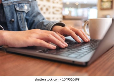 Closeup image of woman's hands using and typing on laptop computer keyboard with coffee cup on the table - Shutterstock ID 1349510699