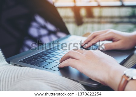 Closeup image of woman's hands using and typing on laptop keyboard 