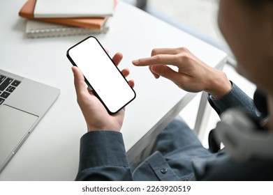 Close-up image of a young Asian male office worker or employee using his smartphone at his office desk. smartphone white screen mockup - Powered by Shutterstock