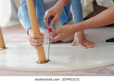 Close-up Image Of Young Couple Fixing Broken Leg Of Coffee Table