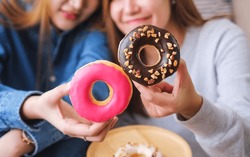 Closeup Image Of A Young Couple Women Holding And Showing A Piece Of Donut Together
