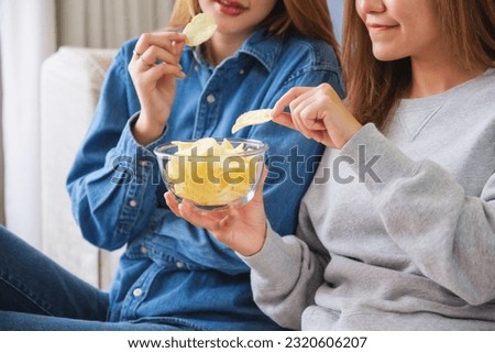 Closeup image of a young couple women sharing and eating potato chips together