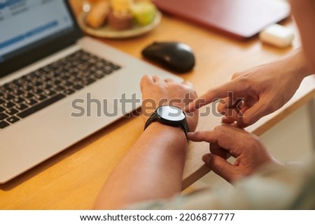Closeup image of young man explaining grandmother how to use smartwatch