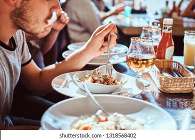 Close-up image of a young man with his friends eating a fresh and healthy salad in an outdoor caf during lunch break - Shutterstock ID 1318568402