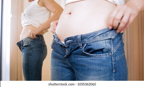 Closeup Image Of Young Woman With Big Belly Wearing Tight Jeans At Mirror