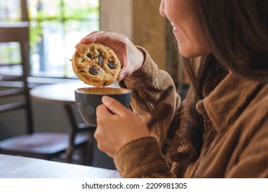 Closeup image of a young woman dipping a chocolate chip cookie into hot drinks - Powered by Shutterstock