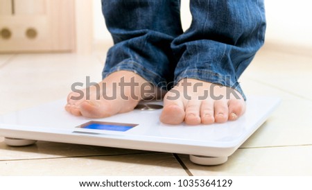 Closeup image of young woman weighting herself at home