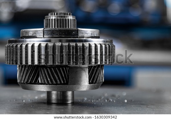 Close-up of an important\
spare part of a car gearbox. Glossy metal gear for planetary\
gearbox.  Metal  autotechnology background, silver metallic with\
gears inside.