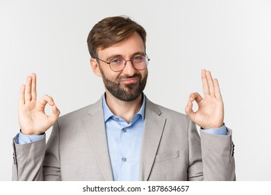 Close-up Of Impressed Boss In Gray Suit And Glasses, Showing Okay Sign And Smiling, Give Approval, Praise Good Job, Standing Over White Background