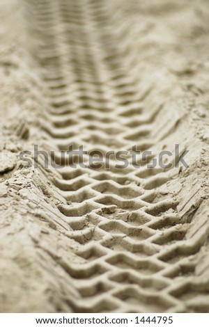 A close-up of the impression left by a vehicle driving over sand.