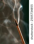 close-up of an incense stick smoking on a dark background. Aromatherapy, Smoking while burning incense. smoke for prayers and meditation. prayer to buddha. incense for relaxation and yoga