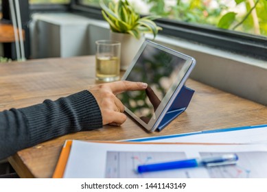 Closeup Of Index Finger Tapping Tablet Screen On Wooden Table