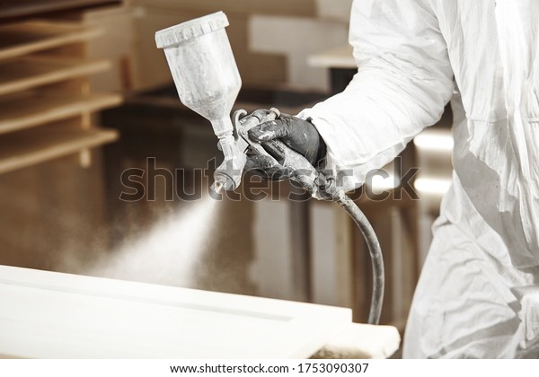 Close-up of industrial worker using paint gun or spray gun for applying paint, airless spraying.