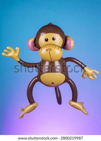 Close-up of an inflatable monkey toy on a purple background, highlighting its playful design and vibrant colors.