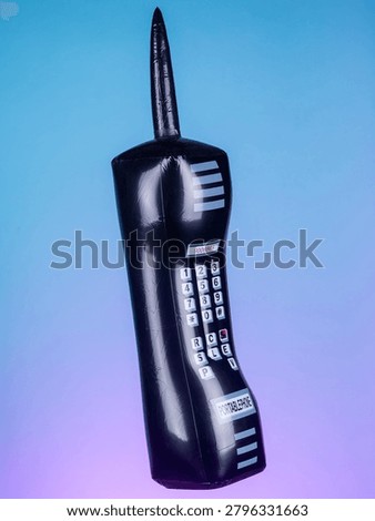 Close-up of an inflatable retro black mobile phone toy on a purple background, highlighting its vintage design and vibrant colors