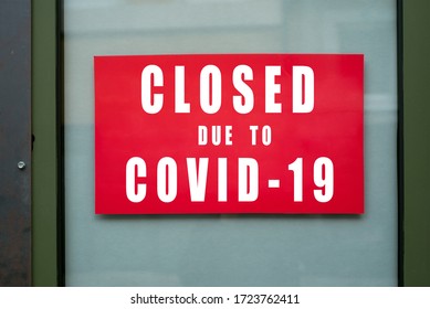 Closeup of information sign on the metallic window of the store front :  Closed due to covid-19