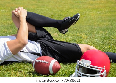 Close-up Of Injured American Football Player Lying On Field With Rugby And Helmet - Powered by Shutterstock