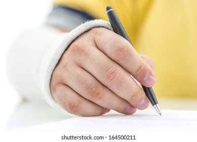 Closeup of injured male hand in plaster signing insurance policy.