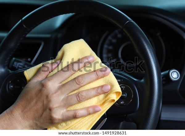 Closeup of inner side car cleaning with yellow\
microfiber cloth by woman owner\'s hand in sunny day. The lovely\
simply family activity.