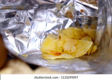 Closeup Inside Empty Foil Bag Of Potato Chips. Fresh Raw Potatoes Lying. Opened Snack Bag.