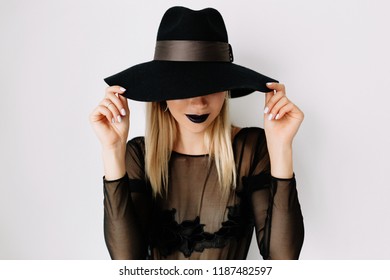 Close-up inside portrait of dreamy elegant woman in black hat covering face, model girl portrait with trendy gothic black make up. Halloween Vampire Woman with black matte lips - Powered by Shutterstock