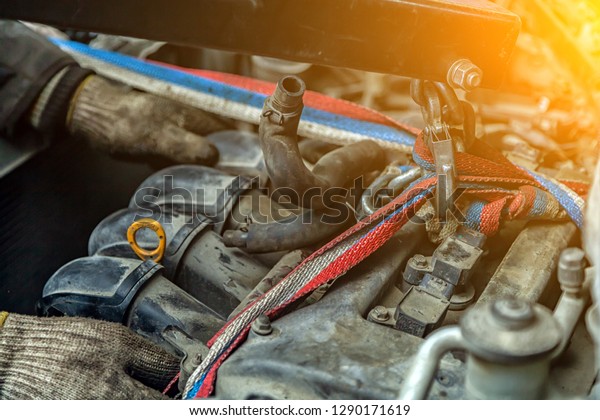Close-up of the installation of the\
motor on an old car using a pneumatic manual crane in the auto\
repair shop. The work of auto mechanics to remove the\
engine