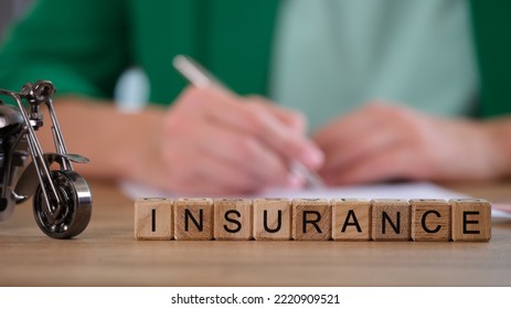 Close-up Of Insurance Word Collected With Wooden Cubes In Row. Small Model Of Motorbike. Insurance Broker On Background