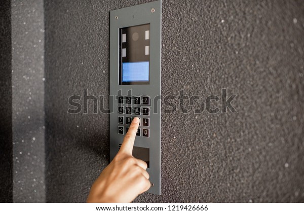 Close-up of intercome keyboard of residential\
building with finger entering\
code