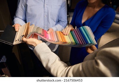 Close-up Of An Interior Designer, Sales Assistant Showing Fabric Samples For Sofa Upholstery To Customers In Furniture Design Showroom. Home Decoration Repair Upholstery Planning.